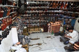 A cobbler busy in preparing the traditional shoes (Peshawari Chappal) to the customer at their workplace in the Provincial Capital