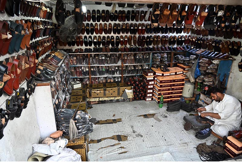 A cobbler busy in preparing the traditional shoes (Peshawari Chappal) to the customer at their workplace in the Provincial Capital
