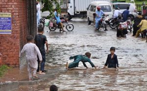 Train passes over a bridge as vehicles lie stranded in deep floodwater below, following heavy monsoon rain at Rahimabad area in the City.