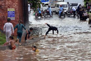 Train passes over a bridge as vehicles lie stranded in deep floodwater below, following heavy monsoon rain at Rahimabad area in the City.