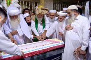 Pir Syed Sajad Shah Badshah and Pir Syed Enayat Shah along with others cutting a cake of Eid Milad-un-Nabi (SAWW)