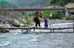 Woman with her child while crossing a temporary bridge at a mountain stream on Harnoi picnic spot.