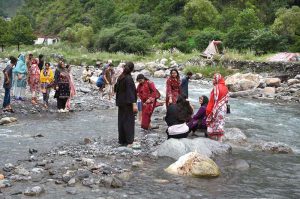 Woman with her child while crossing a temporary bridge at a mountain stream on Harnoi picnic spot.