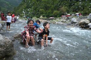 Woman with her child while crossing a temporary bridge at a mountain stream on Harnoi picnic spot.