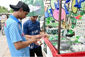 Youngsters purchase festive items from roadside vendor to celebrate Independence Day.