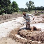 Labourers prepare clay for brick-making at a local brick kiln
