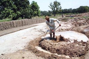 Labourers prepare clay for brick-making at a local brick kiln