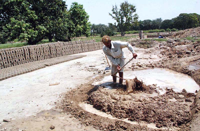 Labourers prepare clay for brick-making at a local brick kiln