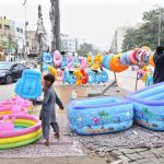 A vendor arranges inflatable swimming pools, toys and other children’s items for sale at a roadside his setup
