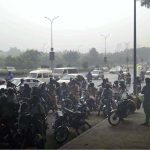 Pedestrians and motorcyclists take shelter under the Srinagar Highway bridge to escape heavy rain in the federal capital
