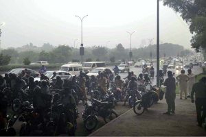 Pedestrians and motorcyclists take shelter under the Srinagar Highway bridge to escape heavy rain in the federal capital
