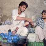 A vendor serves tea to a customer in traditional way at circular Road