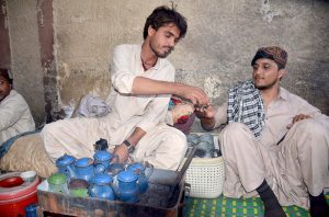 A vendor serves tea to a customer in traditional way at circular Road