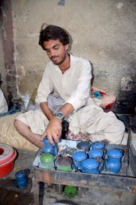 A vendor serves tea to a customer in traditional way at circular Road