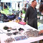 A customer browses through a wide collection of rings, gemstone jewelry and accessories displayed at a roadside stall along Murree Road