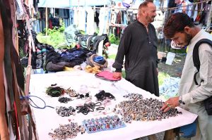 A customer browses through a wide collection of rings, gemstone jewelry and accessories displayed at a roadside stall along Murree Road