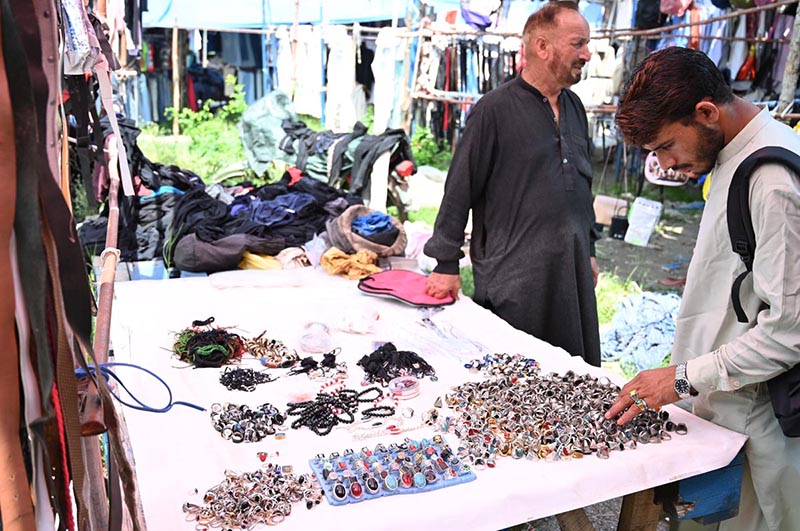 A customer browses through a wide collection of rings, gemstone jewelry and accessories displayed at a roadside stall along Murree Road