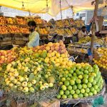 A vendor arranging and displaying seasonal fruits to attract the customers at his setup along Khana Pul