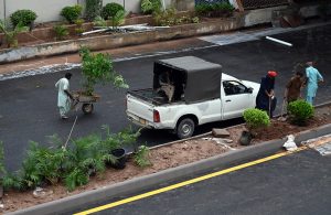 Workers are busy planting saplings on the green belt during the development project of Park Road Underpass in the Federal Capital.