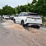 Vehicles wade through rainwater accumulated on PWD Road after heavy rain in the Federal Capital