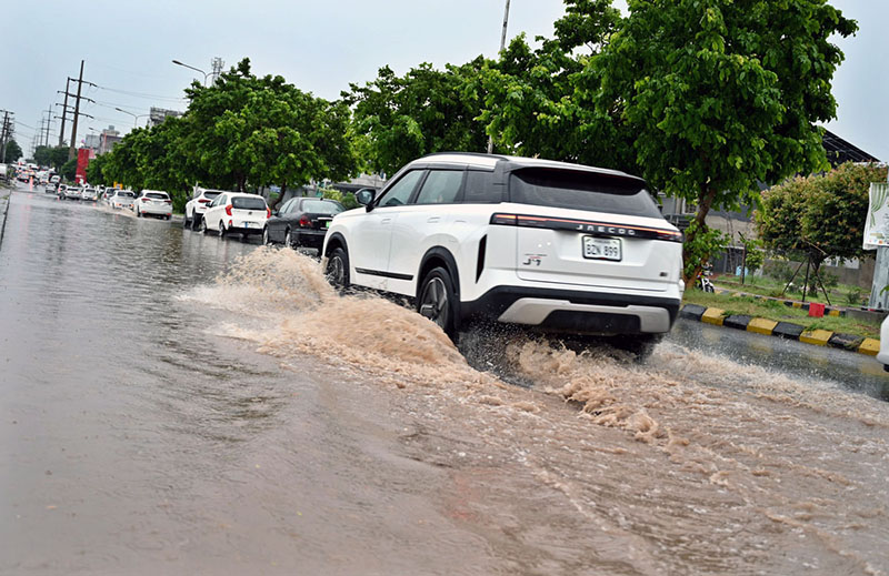 Vehicles wade through rainwater accumulated on PWD Road after heavy rain in the Federal Capital