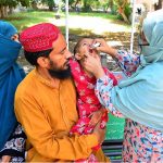 A lady health worker administers polio drops to a child during an anti-polio campaign
