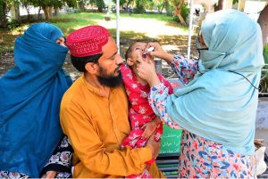 A lady health worker administers polio drops to a child during an anti-polio campaign