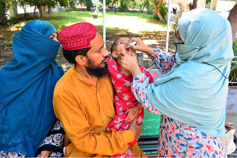 A lady health worker administers polio drops to a child during an anti-polio campaign