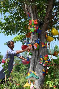 A nursery worker arranges colourful lawn decoration accessories for display and sale while waiting for customers