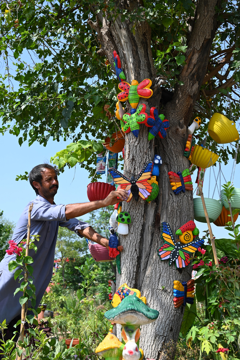 A nursery worker arranges colourful lawn decoration accessories for display and sale while waiting for customers