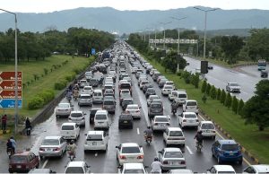 Vehicles wade through rainwater accumulated on PWD Road after heavy rain in the Federal Capital