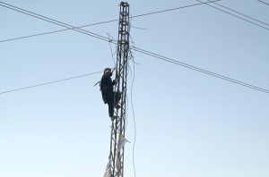 A WAPDA worker busy in fixing electric wires on a pole without proper safety dress or helmet during maintenance work at Zia Masjid