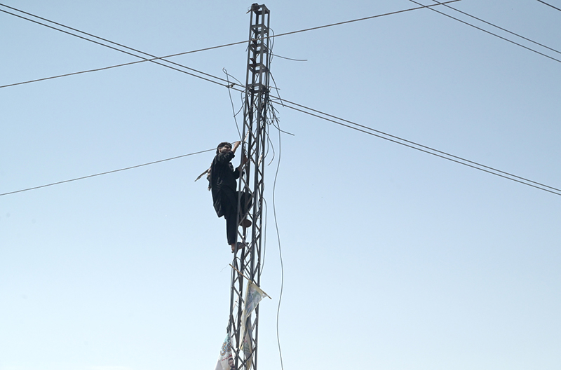 A WAPDA worker busy in fixing electric wires on a pole without proper safety dress or helmet during maintenance work at Zia Masjid