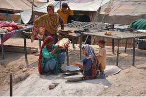 A gypsy family remains busy baking bread in a traditional tandoor outside their makeshift home.