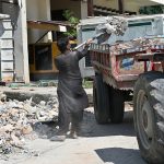 A construction worker loading construction waste into a trolley at an under-construction site
