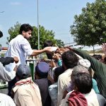 Volunteers distribute food among daily-wage labourers and deserving people from a vehicle at PWD Interchange