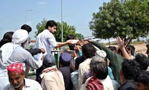 Volunteers distribute food among daily-wage labourers and deserving people from a vehicle at PWD Interchange