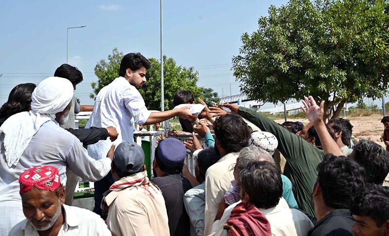 Volunteers distribute food among daily-wage labourers and deserving people from a vehicle at PWD Interchange