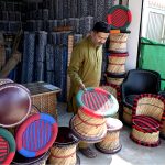 A vendor arranging and displaying wooden stools to attract customers