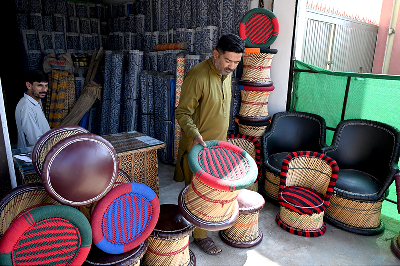 A vendor arranging and displaying wooden stools to attract customers