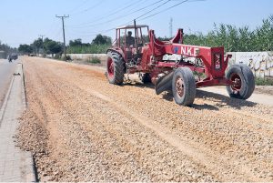 Labourers are busy leveling the ground for road construction as part of development work in Latifabad near a public school