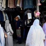 Women purchase used clothes from a vendor at the weekly H-9 Bazaar in the Federal Capital