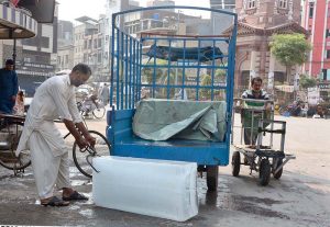 A labourer unloads blocks of ice from a delivery rickshaw to meet customer demand near the historic Clock Tower.