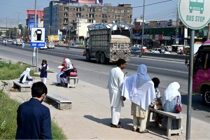 School children waiting for passenger bus at a bus stop on IJP Road as there is no shelter for passengers, need attention of the concerned authorities
