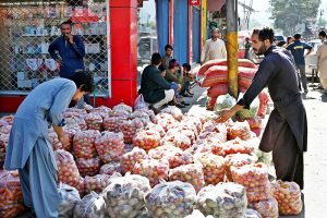 A man buys tomatoes at a market as prices have fallen, making have vegetable more affordable for consumers.
