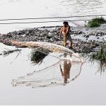 A man casts a fishing net into Rawal Lake