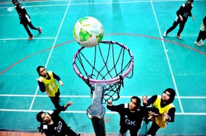 A girls player scores during a netball match between Government Girls High School and Hayat Girls High School at the 5th PNF Netball Cup 2026, held at Hyderabad Club Badminton Hall.