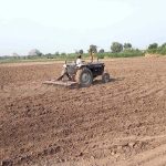 A farmer is busy preparing land for next crop with help of tractor along Lahore Road