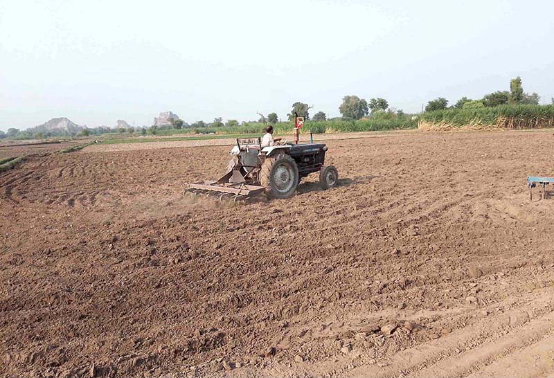 A farmer is busy preparing land for next crop with help of tractor along Lahore Road