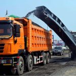 A milling machine loads asphalt material onto a truck during road construction work